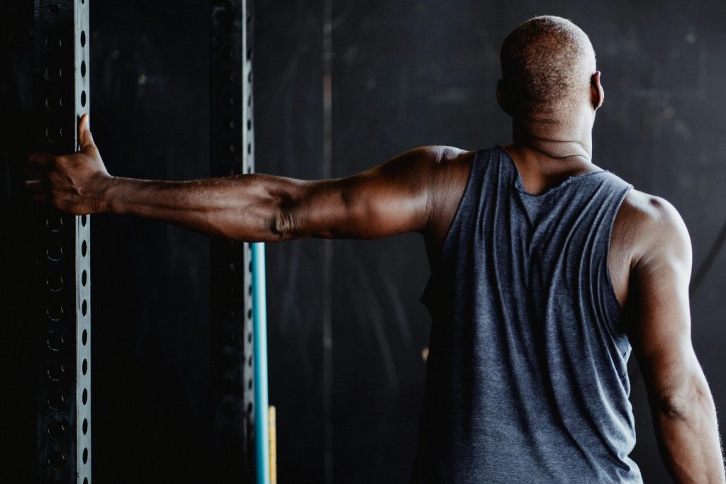 An athletic man stretching his arm in a gym, showcasing strength and flexibility.